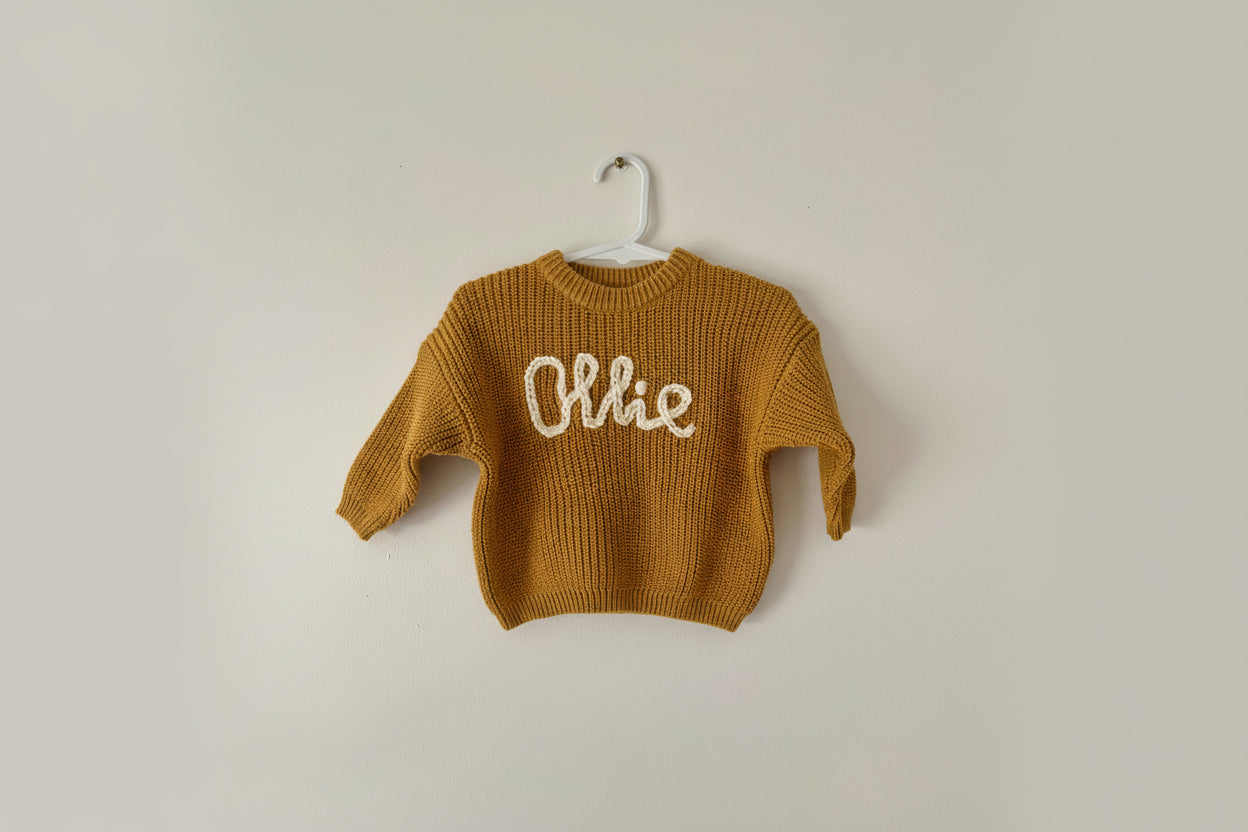 Brown knitted sweater with 'personalised name' on a white background