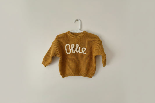 Brown knitted sweater with 'personalised name' on a white background